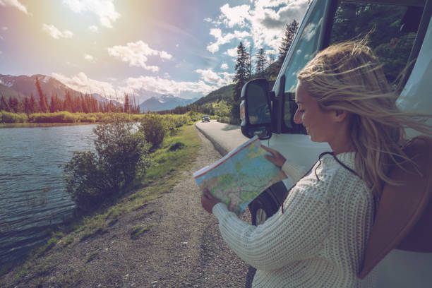 istock Young woman outside van looks at road map 841680734