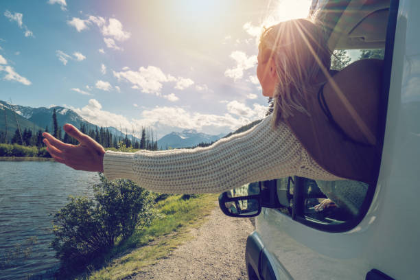 Young woman stretches arm out van window
