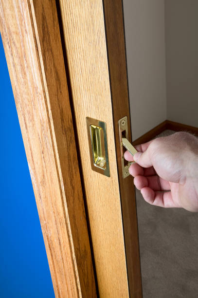 Male hand reaching for a concealed pocket door Male hand reaching for the edge pull on the handle of a concealed wooden pocket door which has been slid back into the wall cavity door lever stock pictures, royalty-free photos & images