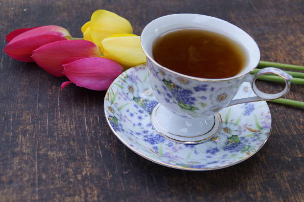 Tea cup, tulip flower, on wooden background. Spring composition.