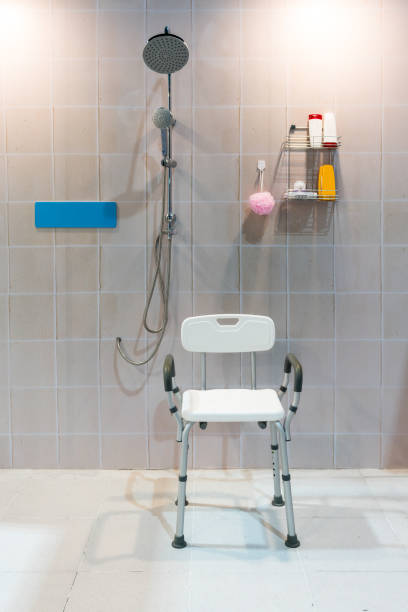Padded shower chair with arms and back in bathroom with bright tile wall and floor. stock photo