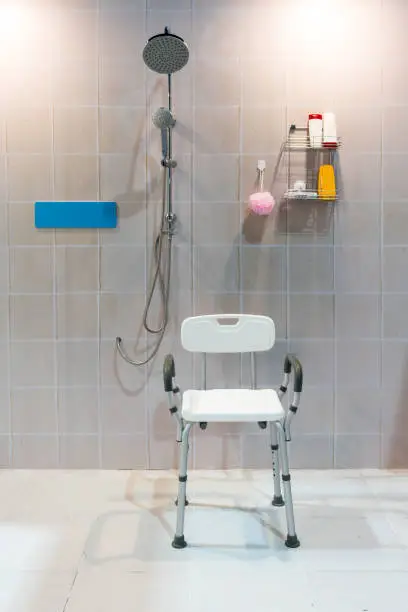 Photo of Padded shower chair with arms and back in bathroom with bright tile wall and floor.