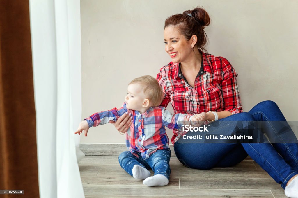 Young mother holding her child Young mother holding her young daughter. Woman and new born girl relax in a bedroom near the windiow. . Mother breast feeding baby. Family at home. Affectionate Stock Photo