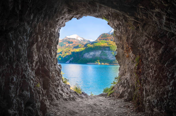 Mountain cave with a colorful view Cavern at the end of a tunnel, with stone walls and a lovely view over the Swiss Alps and the Walensee lake. light at the end of the tunnel photos stock pictures, royalty-free photos & images