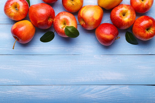 Ripe red apples on blue wooden table with copy space for text . Autumn harvest. Top view