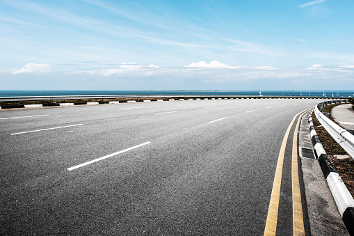 empty asphalt road and blue sea in blue sky