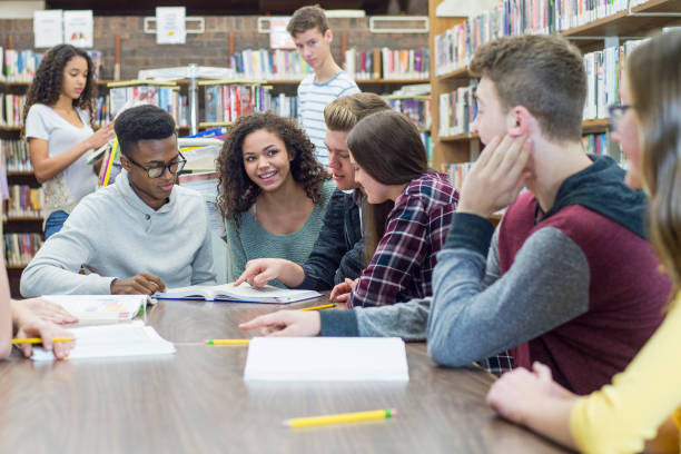 Studying In Library A multi-ethnic group of high school students are indoors in a library. They are wearing casual clothing. They are sitting at a table secondary school activities stock pictures, royalty-free photos & images