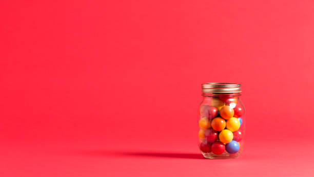 Big jar of jelly beans on yellow background