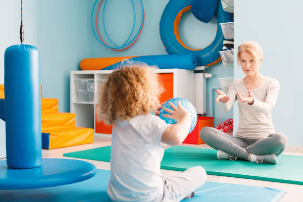 Boy playing with his therapist Boy playing with his therapist using a ball occupational therapy photos stock pictures, royalty-free photos & images