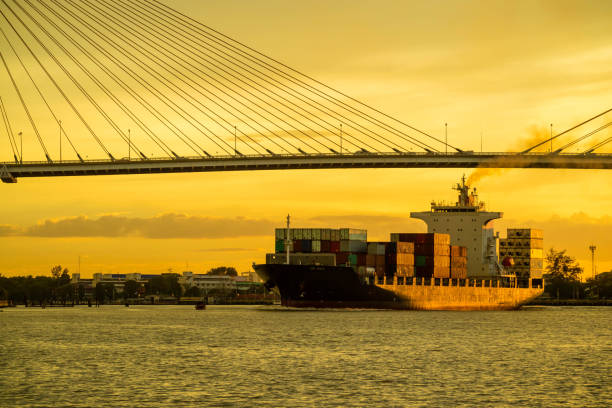 istock Container cargo ocean ship float on river and pass under bridge at sunset twilight with red sky 841745360