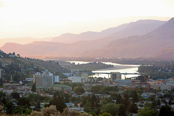 Downtown Kamloops With Evening Sunlight In The Valley Behind Early evening Dusk over Kamloops BC. Thompson River winds through downtown. Layers of hills with sunlight. Old homes in downtown district. kamloops stock pictures, royalty-free photos & images