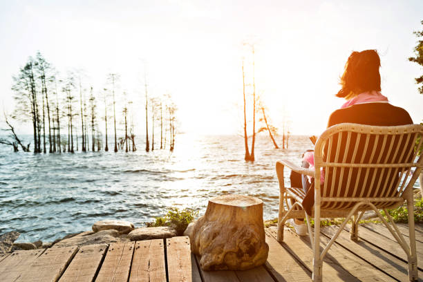 Young woman reading a book while sitting by the lake.
