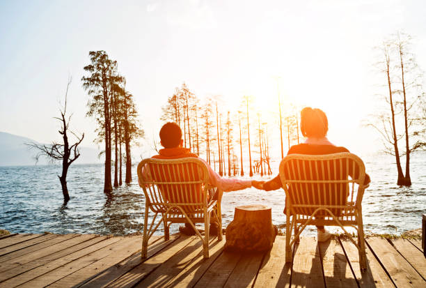 пара наслаждаясь закатом озера - romance lake chair sunset стоковые фото и изображения