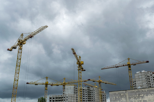 Construction cranes developing residential buildings under the stormy sky
