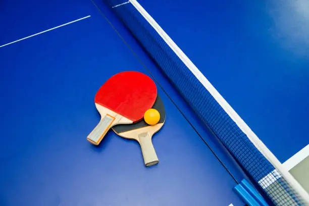 Ping-Pong paddles with ball on table.