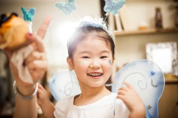 Photo of A girl who costumes a fairy is playing with a magic wand.