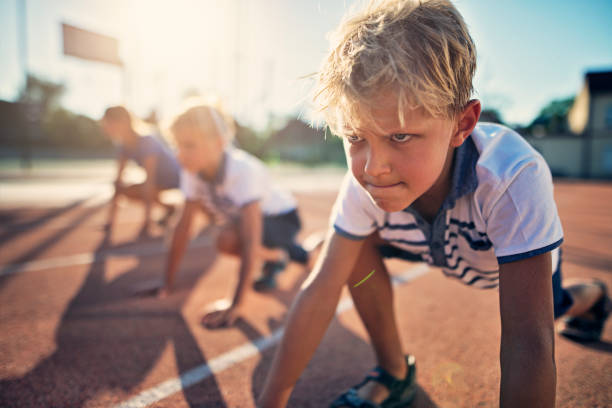 Kids preparing for track run race Kids preparing for track run race start. Kids are waiting for the signal for the race to begin. Closeup of little boy's determined face.
 toughness stock pictures, royalty-free photos & images