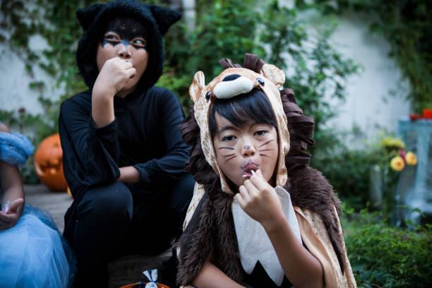 niños sentarse fuera y comer dulces. - costume halloween lion baby fotografías e imágenes de stock