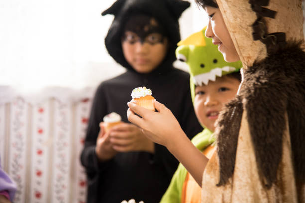 los niños comen cupcakes deliciosamente en la cocina. - costume halloween lion baby fotografías e imágenes de stock