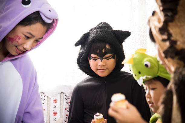 los niños comen cupcakes deliciosamente en la cocina. - costume halloween lion baby fotografías e imágenes de stock