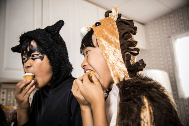 남자는 부엌에서 컵 케이크 맛있게 먹는다. - costume halloween lion baby 뉴스 사진 이미지