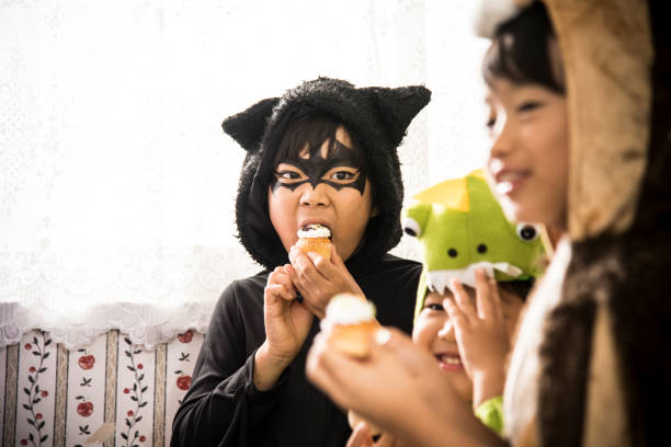 남자는 부엌에서 컵 케이크 맛있게 먹는다. - costume halloween lion baby 뉴스 사진 이미지