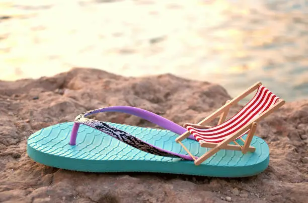 flipflop with beachchair on a stone close up behind the sea