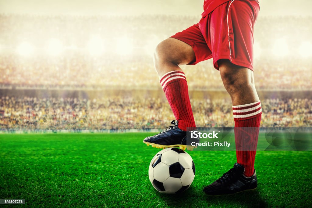 feet of red team football player on soccer ball for kick-off in the stadium Soccer Stock Photo