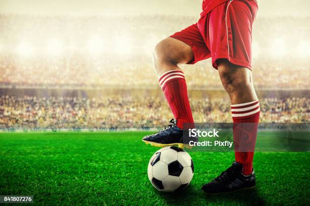 Feet Of Red Team Football Player On Soccer Ball For Kickoff In The Stadium Stock Photo - Download Image Now