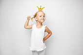 Beautiful little girl with paper crown posing on white backgroun