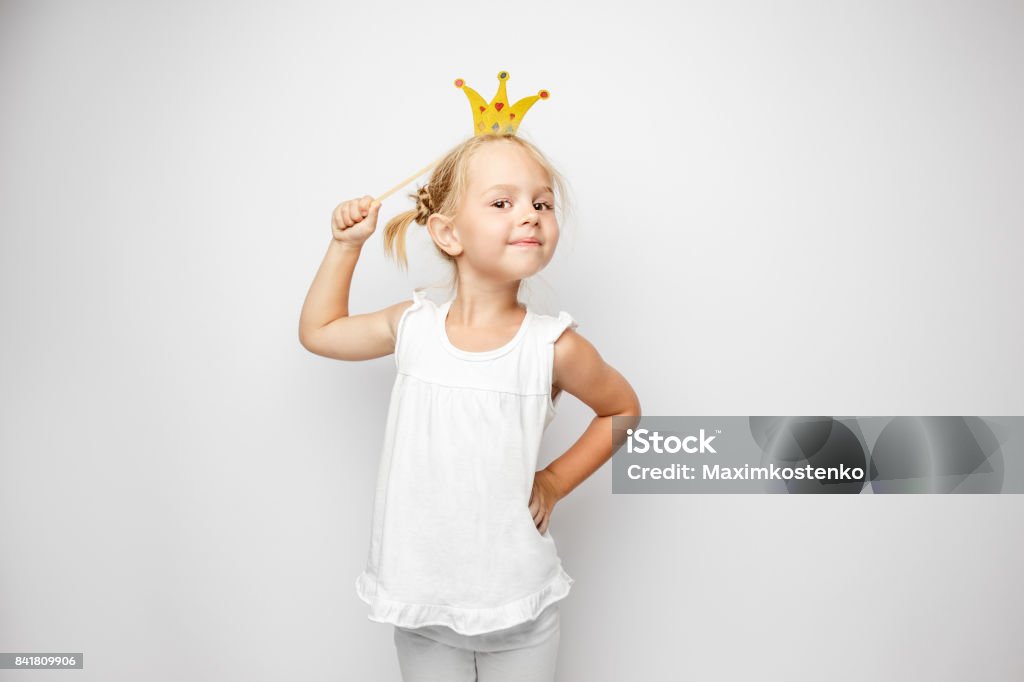 Beautiful little girl with paper crown posing on white backgroun Beautiful little girl with paper crown posing on white background at home Princess Stock Photo