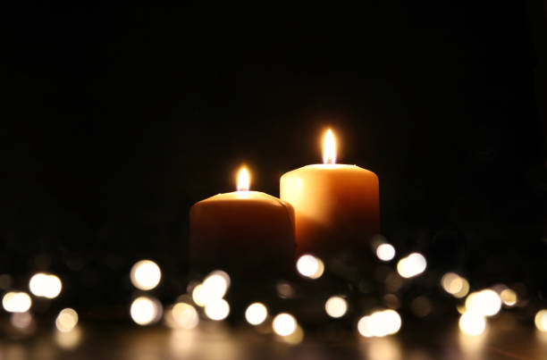 istock Burning candles over black background with bokeh glitter lights 841814330