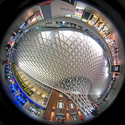 This photo is taken by AllWinner's v3-sdv on Kings Cross train station platform in London. There are shops and  commuters in the background with the architectural ceiling the prominent feature.