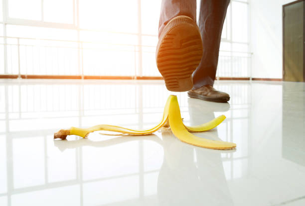 Businessman stepping on banana skin in office building hall.