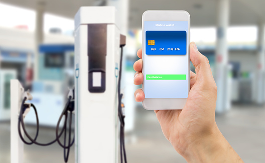 hand holding the phone with mobile wallet to pay online at electric car charging station.