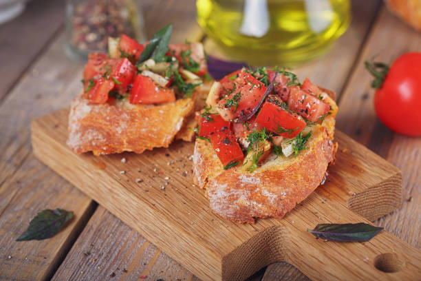 bruschetta with chopped tomatoes, basil and herbs on grilled crusty bread. - bruschetta cutting board italy olive oil imagens e fotografias de stock