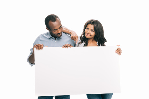 happy young african american couple holding blank banner isolated on white