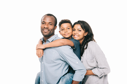 beautiful happy african american parents with adorable son hugging and smiling at camera isolated on white