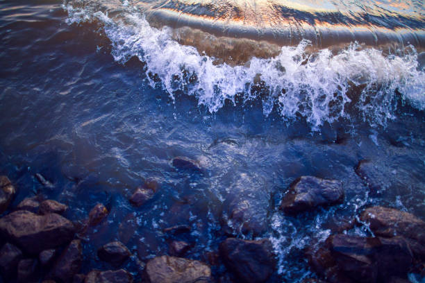 Wave crest on the Mississippi River crashing onto the bank shoreline edge