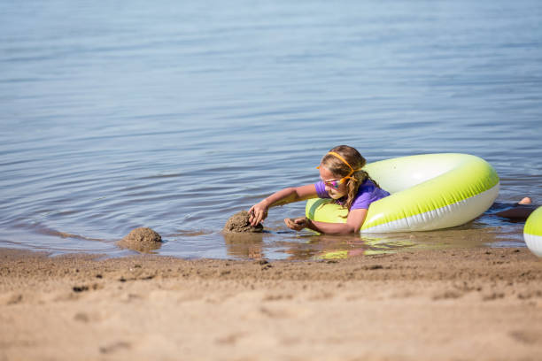 istock Girl Playing In Sand At Beach With Innertube Float 841876328