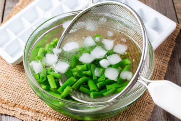 ゆで野菜、ブランチング後氷水で緑色の豆 - 凍っている水 ストックフォトと画像