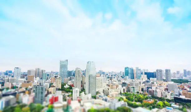 Photo of city skyline bird eye aerial view from tokyo tower under dramatic sunny and morning blue cloudy sky in Tokyo, Japan. Miniature Tilt-shift effect