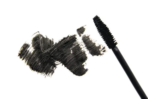 Photo of Stroke of black mascara close-up macro with applicator brush, isolated