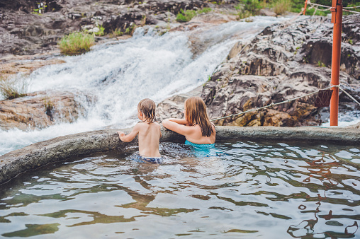 Geothermal spa. Mother and son relaxing in hot spring pool against the background of a waterfall. hot springs concept