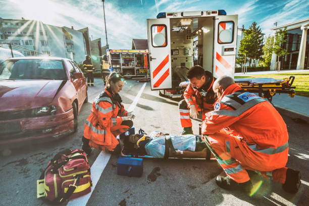 Paramedics providing first aid Paramedics providing first aid to man injured in car accident. emt stock pictures, royalty-free photos & images