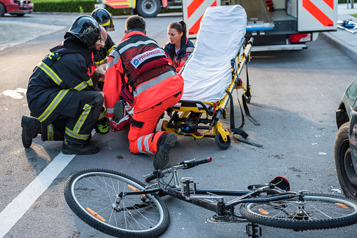 Firefighters and paramedics team rescuing injured cyclist.