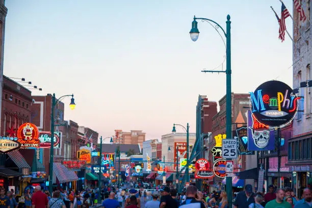 Memphis, TN, USA - June 25, 2017: View of a crowd of tourists enjoying the music clubs and retail establishments that line the famous music district of Beale Street in downtown Memphis, TN at dusk.  Beale Street is on the U.S. National Register of Historic Places.