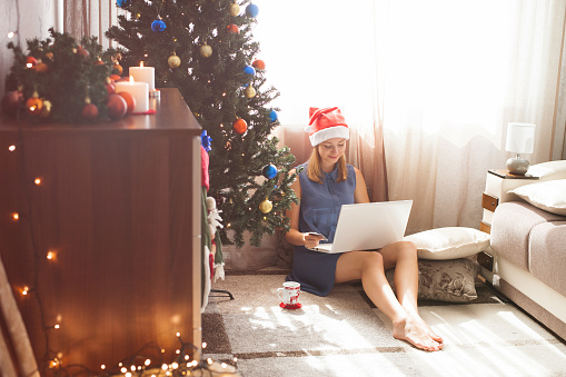 Cute young woman shopping online - holding credit card and feeling happy in awaiting Christmas holiday