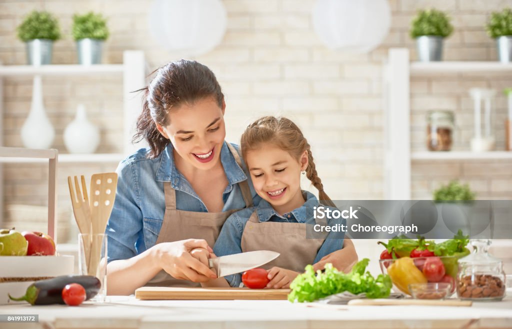 Happy family in the kitchen. Healthy food at home. Happy family in the kitchen. Mother and child daughter are preparing the vegetables and fruit. Mother Stock Photo
