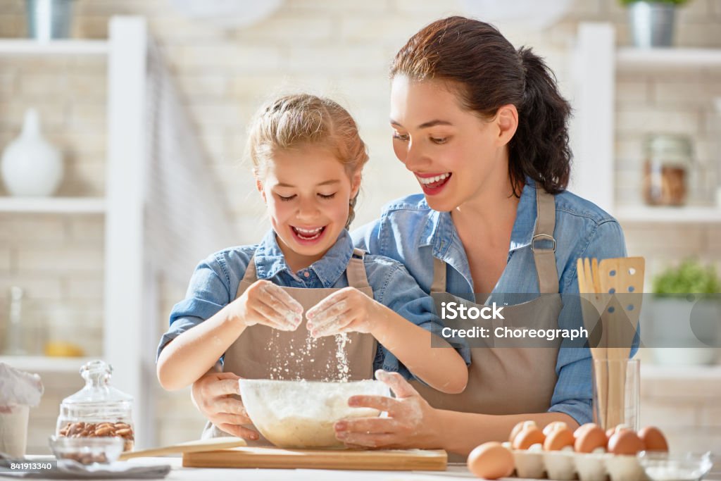 Happy family in the kitchen. Happy loving family are preparing bakery together. Mother and child daughter girl are cooking cookies and having fun in the kitchen. Homemade food and little helper. Mother Stock Photo